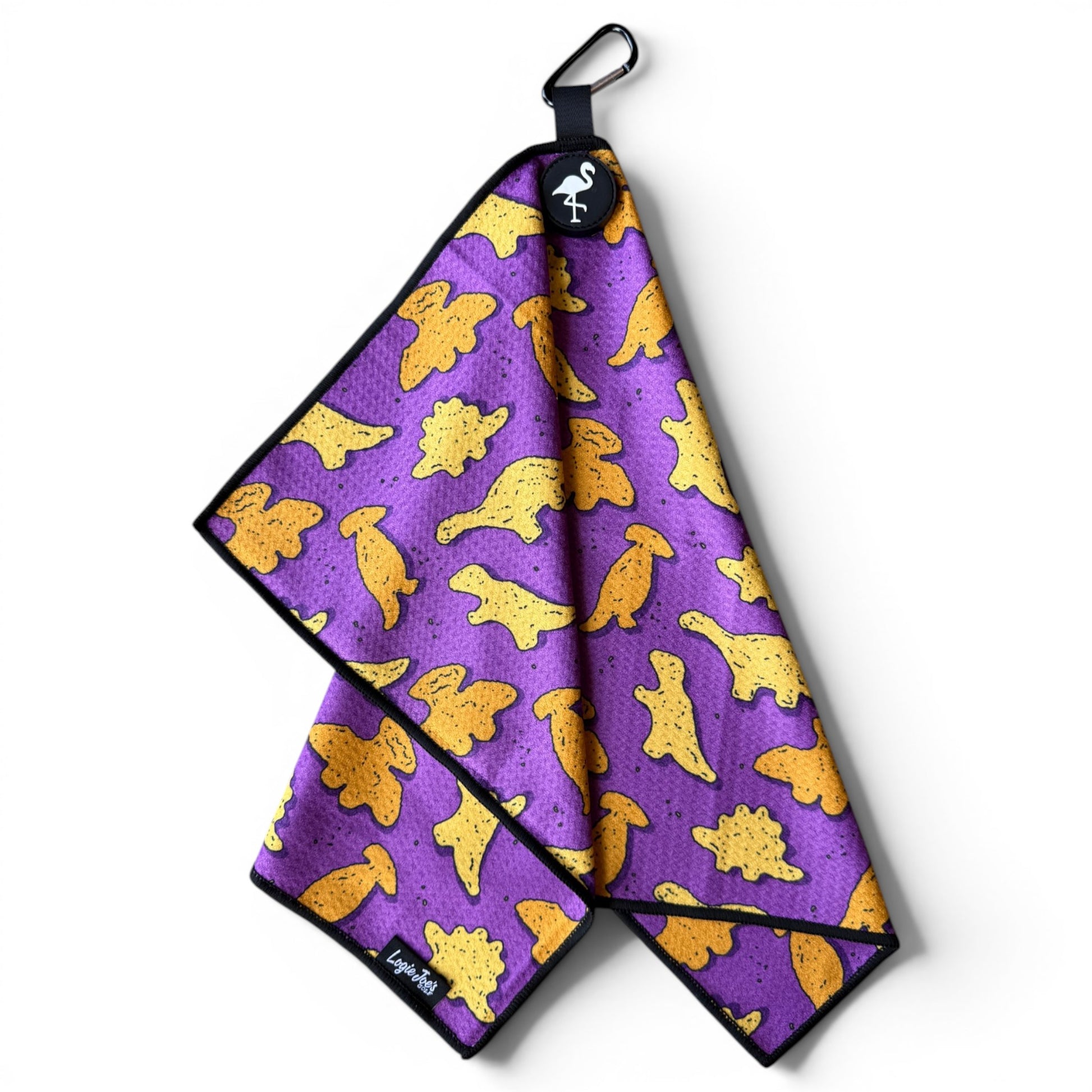 The Purple Dino Chicken Nugget Golf Towel is a 24” x 16” microfiber towel with a yellow dinosaur pattern, black trim, flamingo logo tag, and includes both a magnetic clip and carabiner for easy attachment.