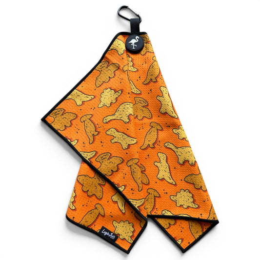 The Orange Dino Chicken Nugget Golf Towel (24” x 16”) is a microfiber towel featuring a playful dino chicken nugget pattern, black border, magnetic clip, carabiner, and round logo tag attached at the top corner.