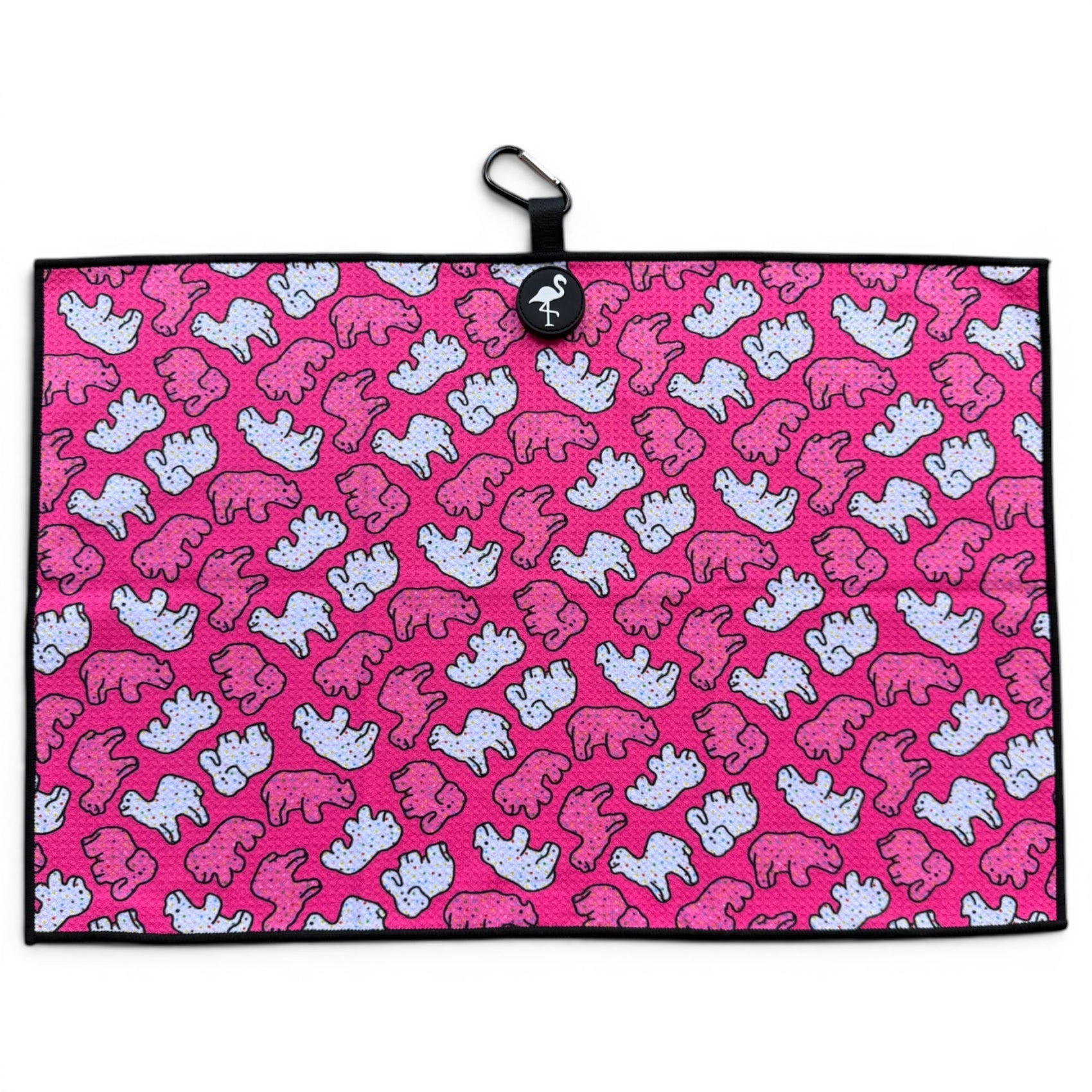 The Frosted Animal Cookie Golf Towel is a 24” x 16” pink microfiber towel with a white and pink cartoon elephant pattern, black border, and features a magnetic clip with carabiner, making it a premium golf accessory.
