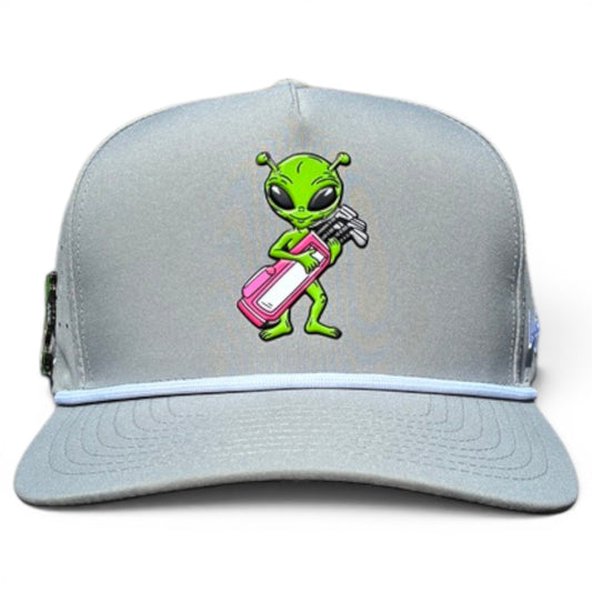 The Alien Caddy Golf Hat is a light gray adjustable snapback cap featuring a green cartoon alien with a pink and white golf bag on the front. It includes a built-in magnetic ball marker holder plus marker for added convenience.