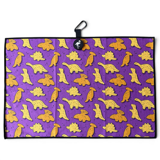 The Purple Dino Chicken Nugget Golf Towel (24” x 16”) features yellow and orange cartoon dinosaurs on a purple microfiber towel with black border, hanging loop, magnetic clip, and carabiner—a stylish premium accessory for golfers.