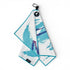 The 90s Party Cup Golf Towel is a 24x16" premium double-sided white microfiber towel with teal and purple abstract patterns, teal edging, black loop, magnetic round tag with a white flamingo icon, and carabiner clip. Displayed on white background.