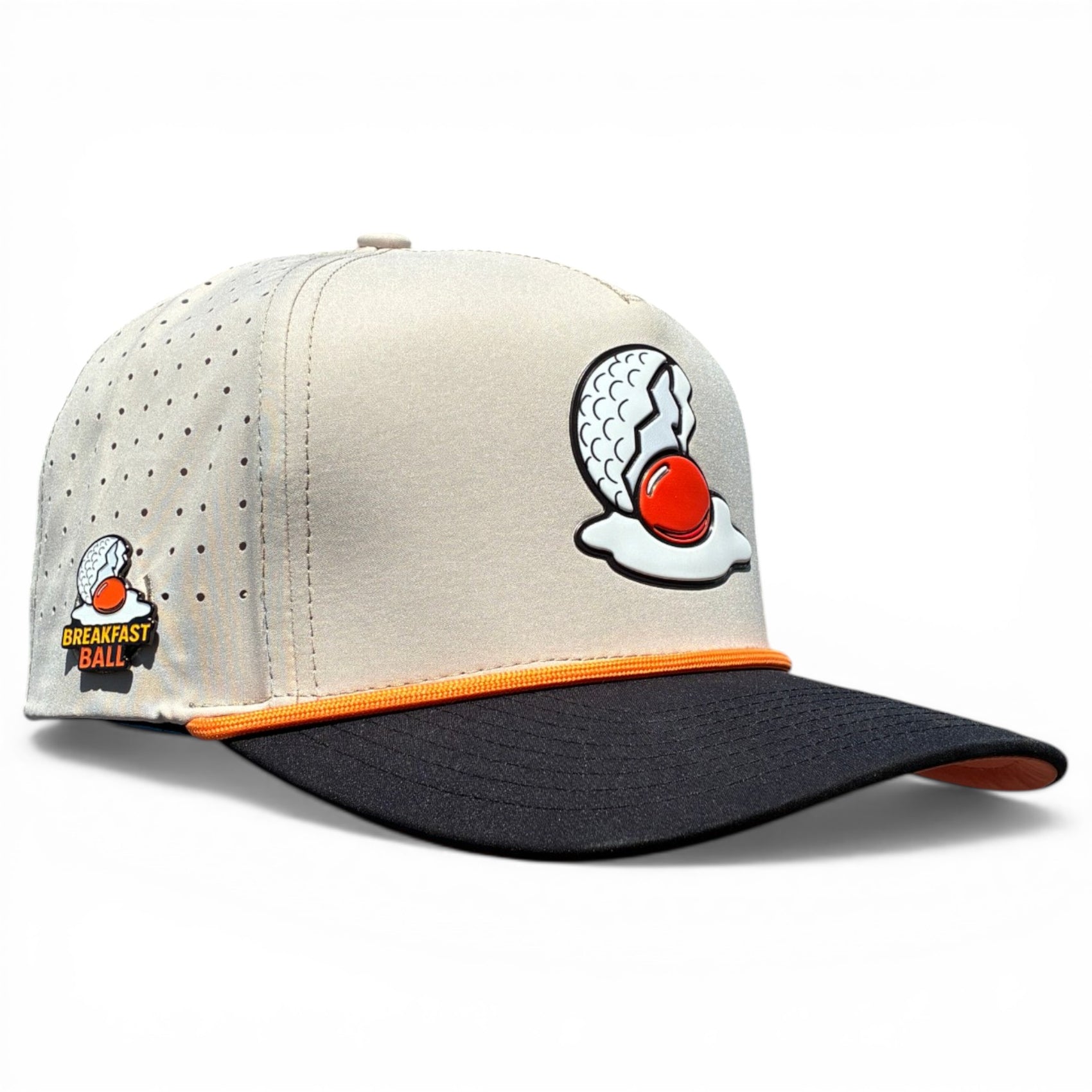 The Breakfast Ball Golf Hat in Mulligan Tan is an adjustable snapback cap with a built-in magnetic ball marker holder, included marker, and features Breakfast Ball branding on the front and side.