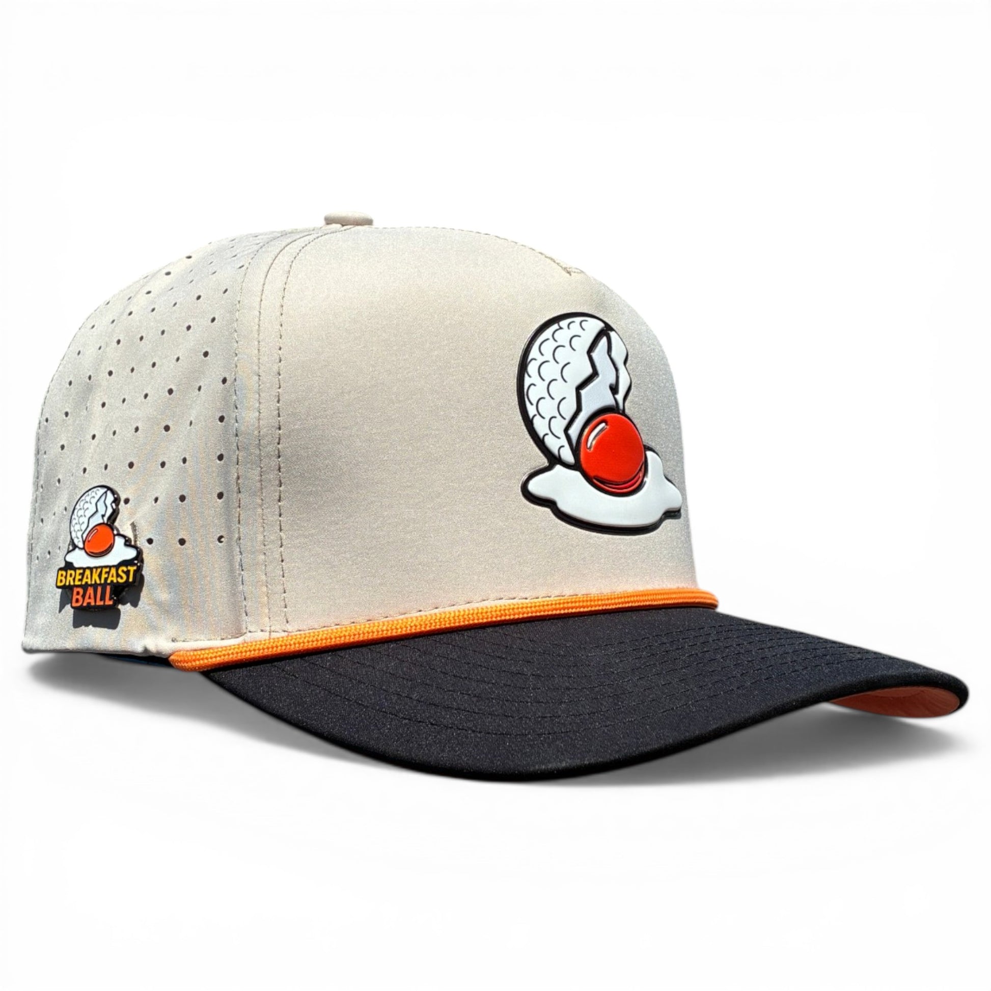 The Breakfast Ball Golf Hat in Mulligan Tan is an adjustable snapback cap with a built-in magnetic ball marker holder, included marker, and features Breakfast Ball branding on the front and side.