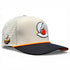 The Breakfast Ball Golf Hat in Mulligan Tan is an adjustable snapback cap with a built-in magnetic ball marker holder, included marker, and features Breakfast Ball branding on the front and side.