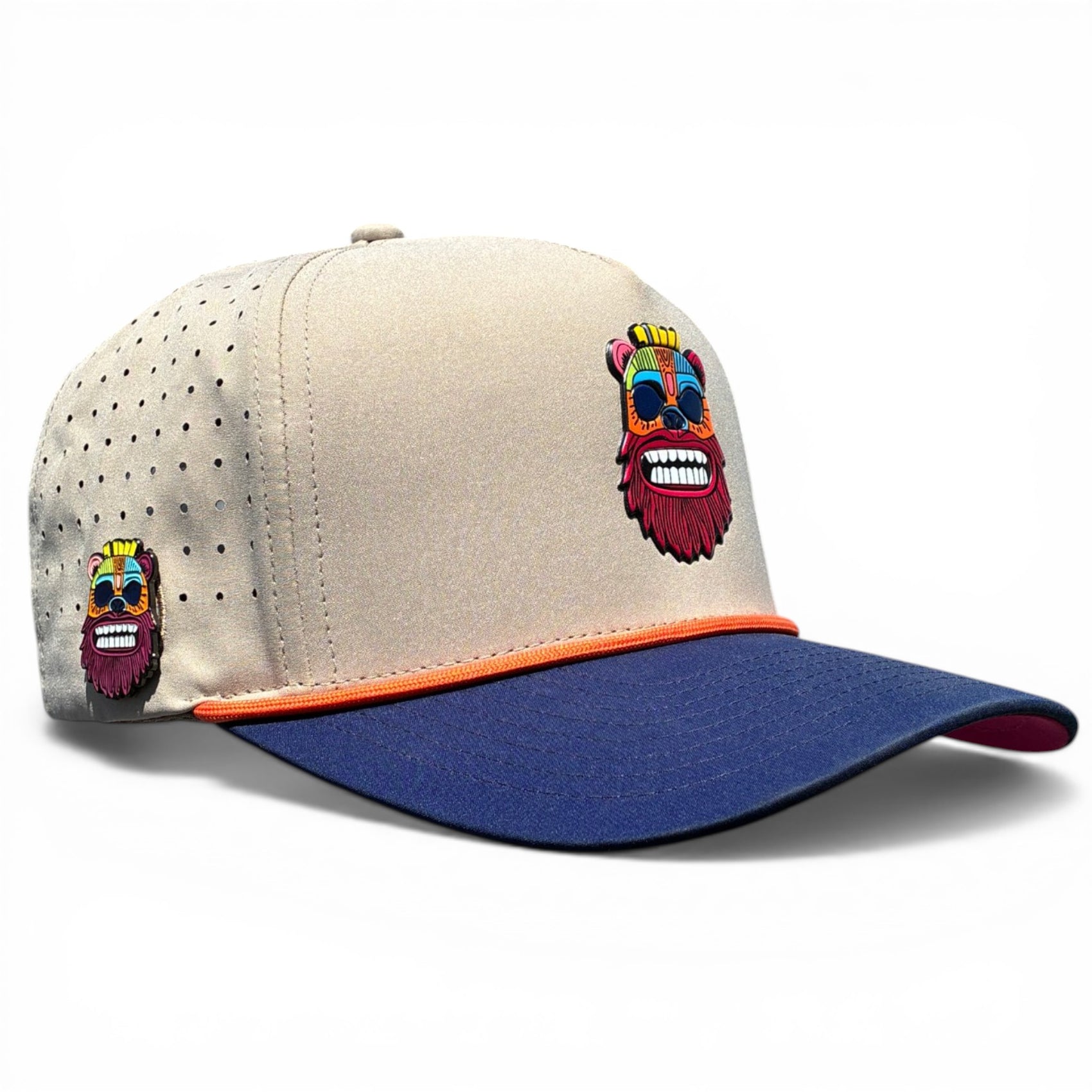 The Tiki Bear Golf Hat is a beige and blue adjustable snapback cap with orange trim, featuring a colorful bearded face design, ventilation holes, and a built-in magnetic ball marker holder with marker included.