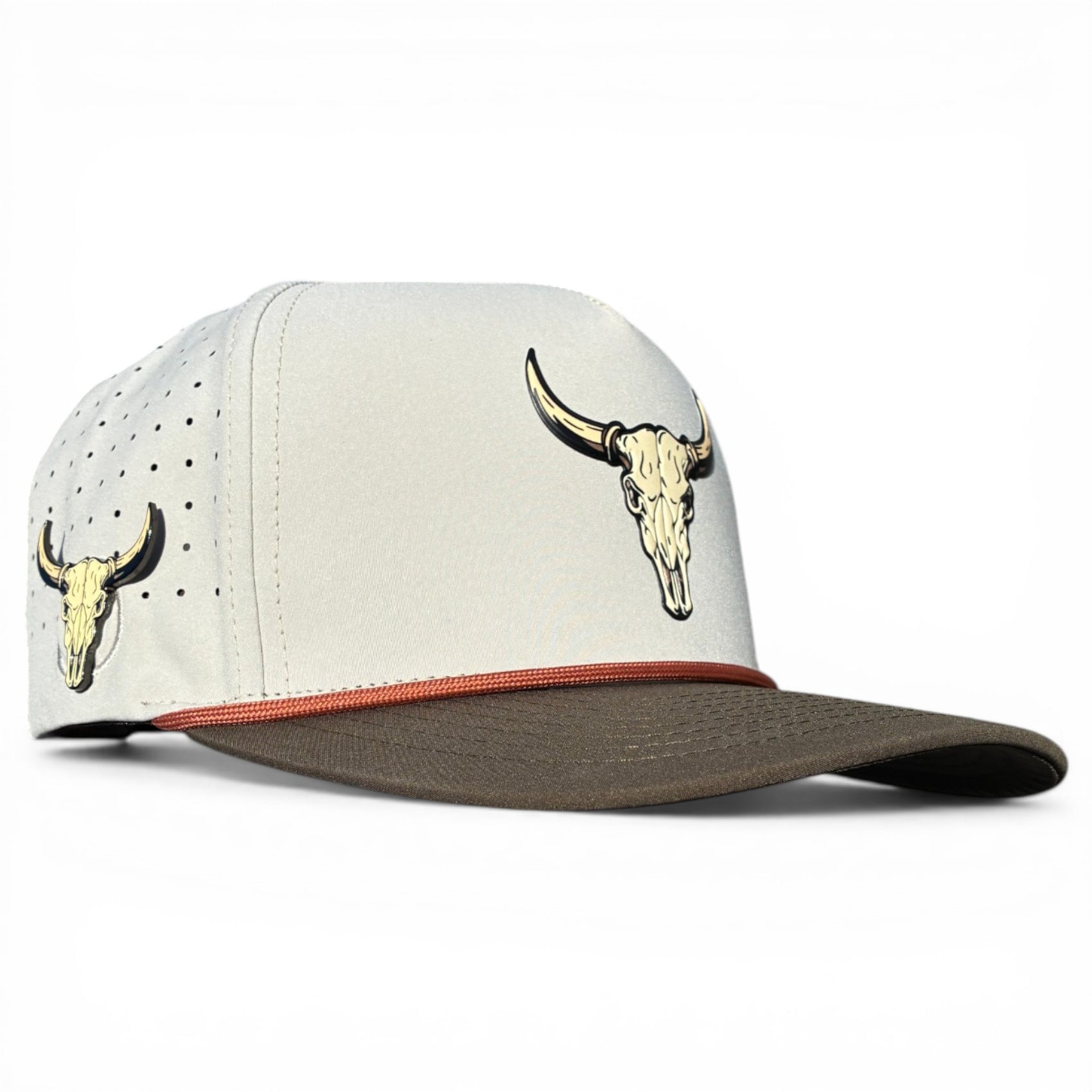 The Longhorn Golf Hat is a light gray snapback cap with a brown curved brim, tan bull skull graphics, ventilation holes, a thin red stripe above the brim, and an adjustable fit. Includes built-in magnetic ball marker holder and marker.