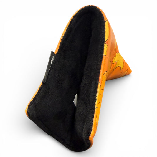 A triangular stand inspired by the Dino Nugget Blade Putter Headcover, featuring a bright orange, yellow-patterned exterior and black fuzzy lining, designed to securely hold your phone or tablet upright.