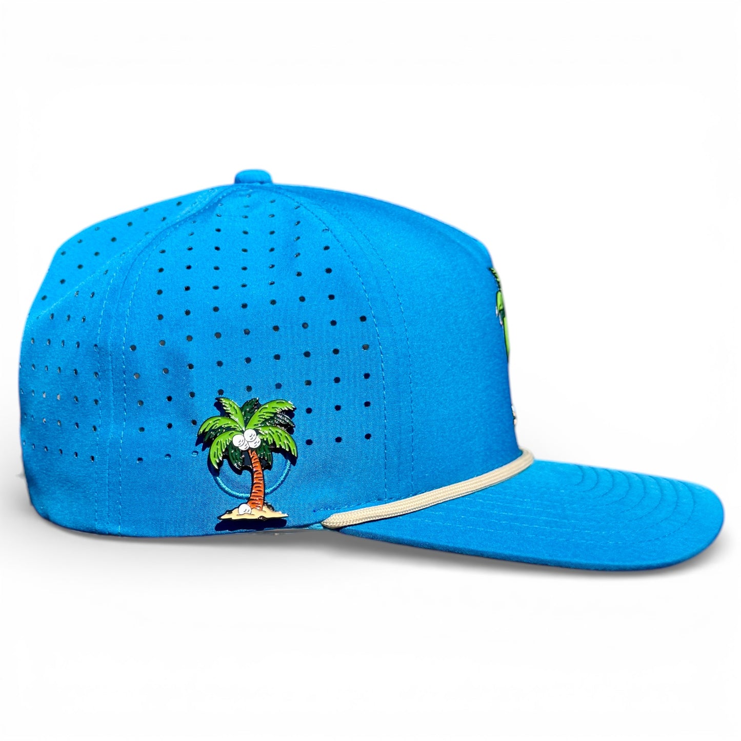 The Fairway Palms Golf Hat is a bright blue snapback cap with small ventilation holes, an embroidered palm tree island on the side, a curved brim with beige trim, plus a built-in magnetic ball marker holder and adjustable fit.