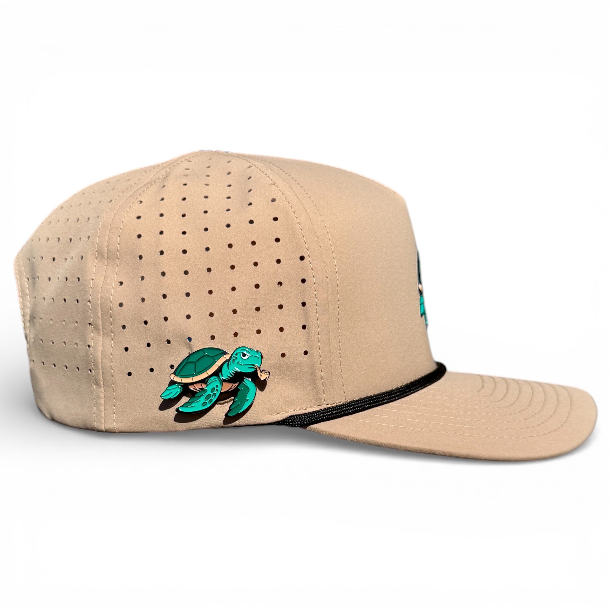 The Salty Turtle Golf Hat is a beige snapback cap with black brim trim, a colorful embroidered sea turtle on the side, and an adjustable fit. It features a built-in magnetic holder with included ball marker. One size fits most.