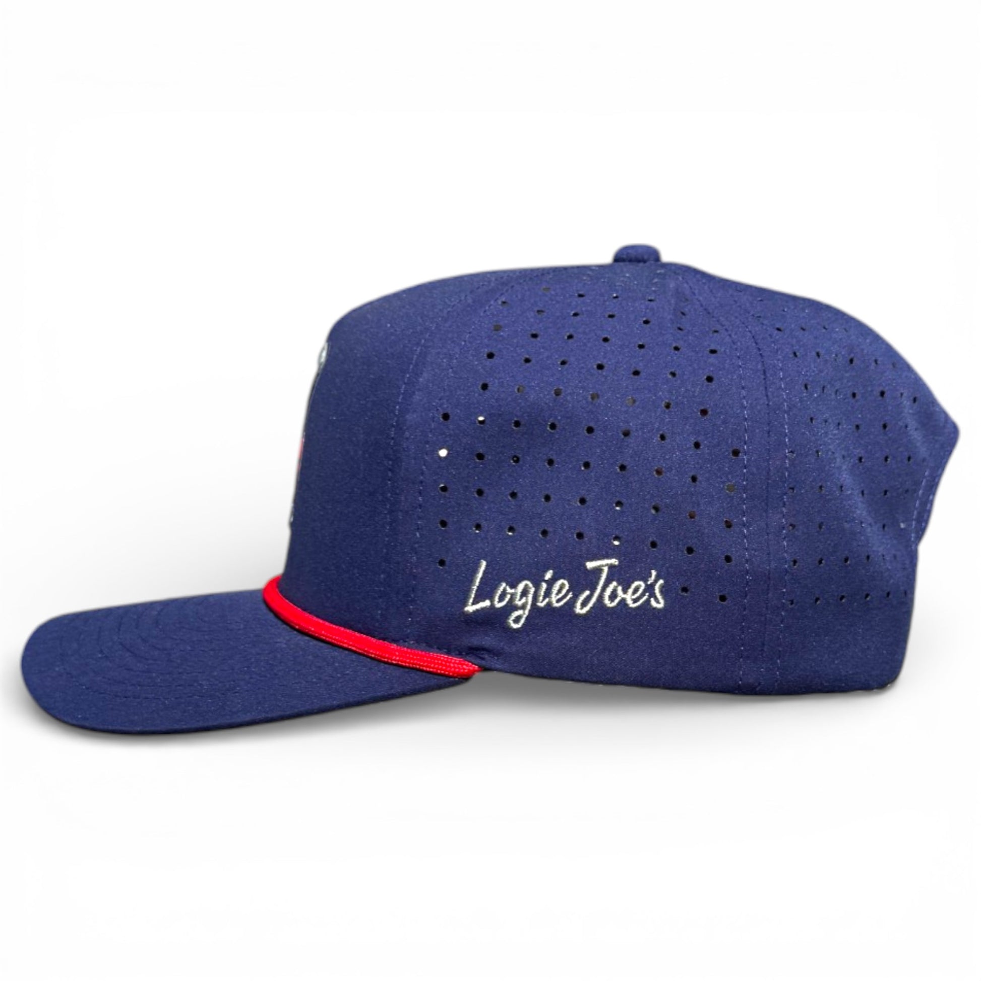 The Crab Trap Golf Hat is a dark blue adjustable snapback with ventilation holes, red brim trim, and "Logie Joes" embroidered in white on the side. It features a built-in magnetic ball marker holder with marker included. One size fits most.