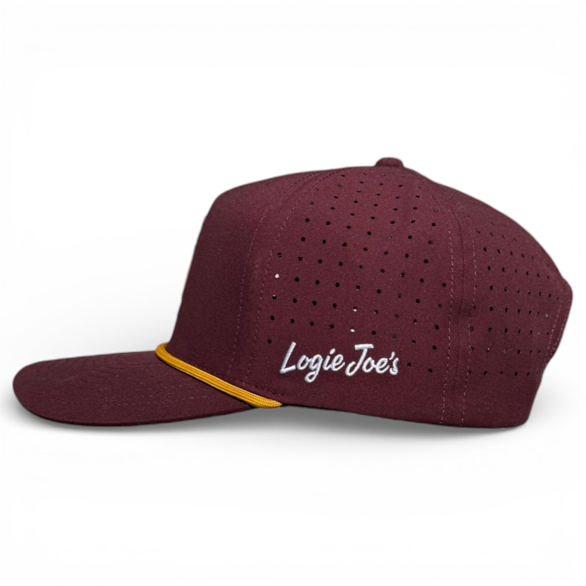 The Cold One Golf Hat is a maroon snapback cap with small vents, a yellow stripe above the visor, and "Logie Joes" embroidered in white. It features an adjustable fit and a built-in magnetic ball marker holder with marker included. Displayed on a white background.