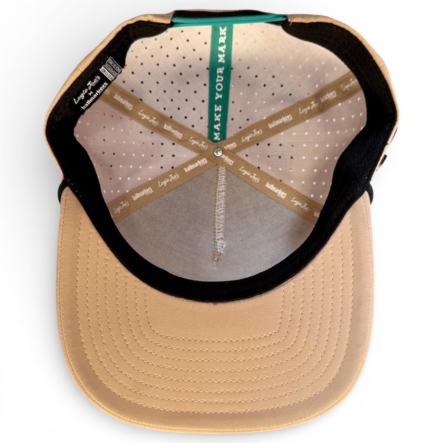 Salty Turtle Golf Hat (snapback, adjustable, one size) in beige shown from above, featuring inside lining with branded labels, a green "MAKE YOUR MARK" strip, stitched details, and built-in magnetic ball marker holder with marker included.