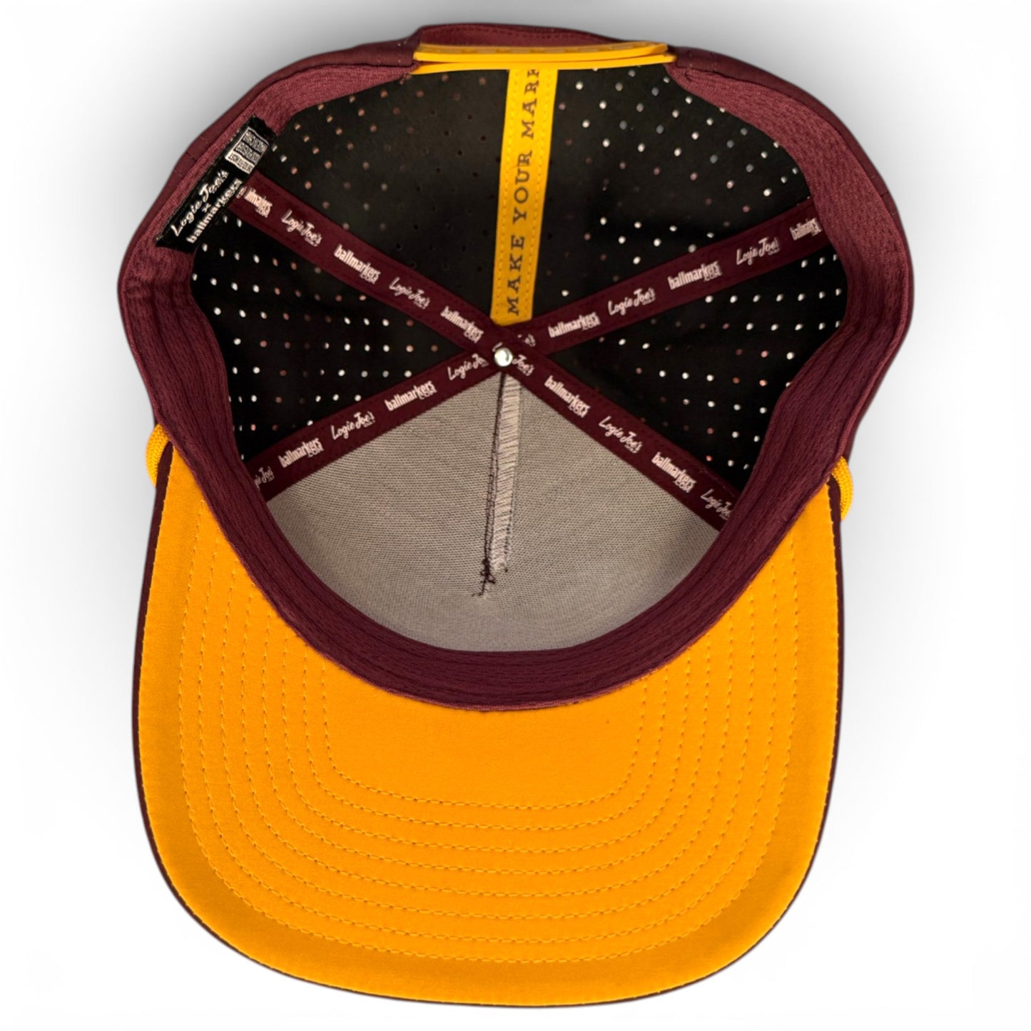 Top-down view of the inside of the Cold One Golf Hat Snapback Cap, showing stitching, inner labels, a built-in magnetic holder with included ball marker, and "MAKE YOUR MARK" printed along one internal crossband.