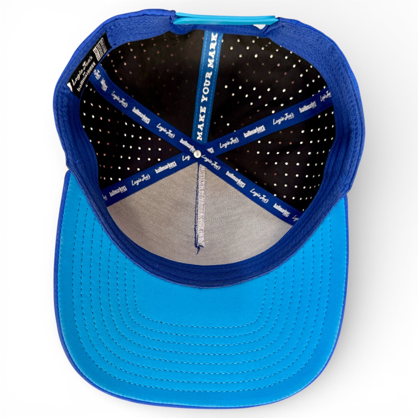 An overhead view of the blue Water Ball Golf Hat | Snapback Cap shows black and blue panels with "MAKE YOUR MARK" and "Lids" on the inner bands. The adjustable cap features a built-in magnetic ball marker holder with marker, perfect for golfers.