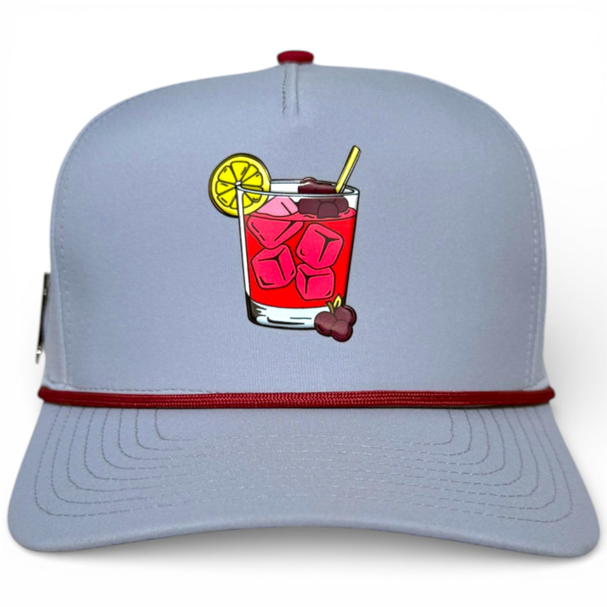 The Transfusion Golf Hat is a light gray snapback cap with a maroon stripe, red cocktail graphic, and an adjustable fit. It features a built-in magnetic ball marker holder and comes with the marker for convenience on the course.
