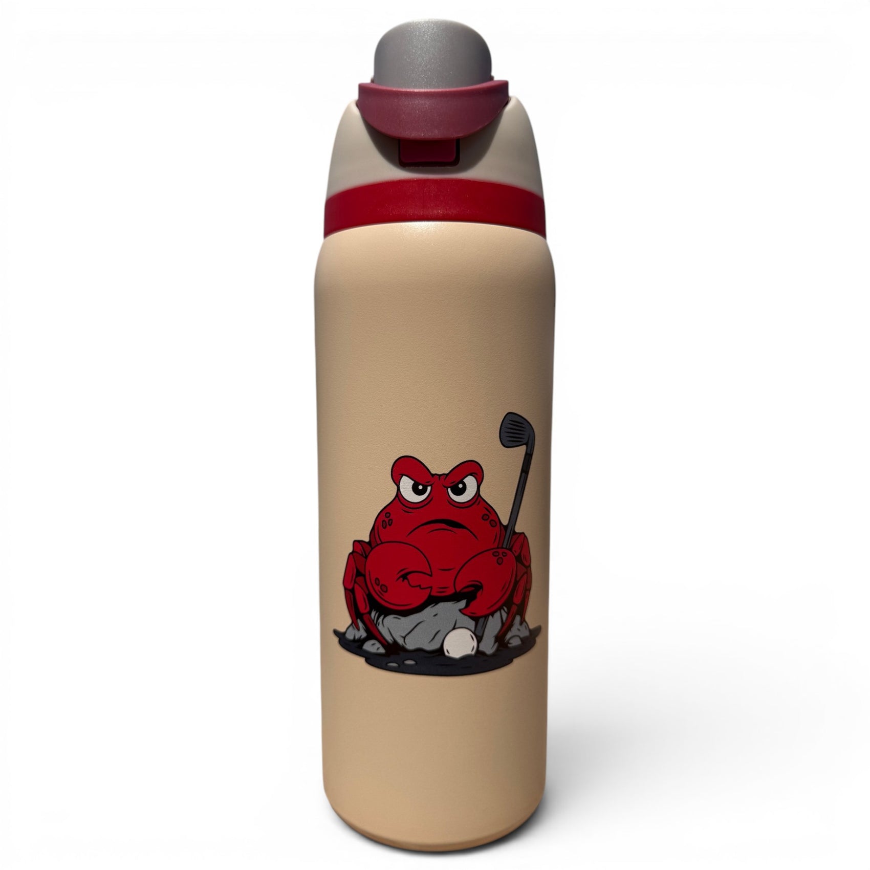 The 32oz Hydration Bottle – Crab Trap is a beige insulated stainless steel bottle with a red flip straw lid and handle, featuring an illustration of a grumpy red crab holding a golf club on a rock beside a golf ball.