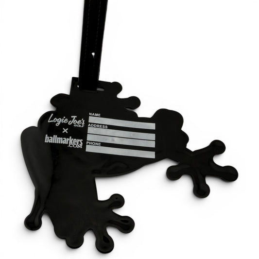The Tree Frog Clip-On Tag is a black frog-shaped accessory for bags or luggage, with fields for Name, Address, and Phone. Features Logie Joes and ballmarkers.com logos and includes a black hanging strap. Ideal as a golf or travel tag.