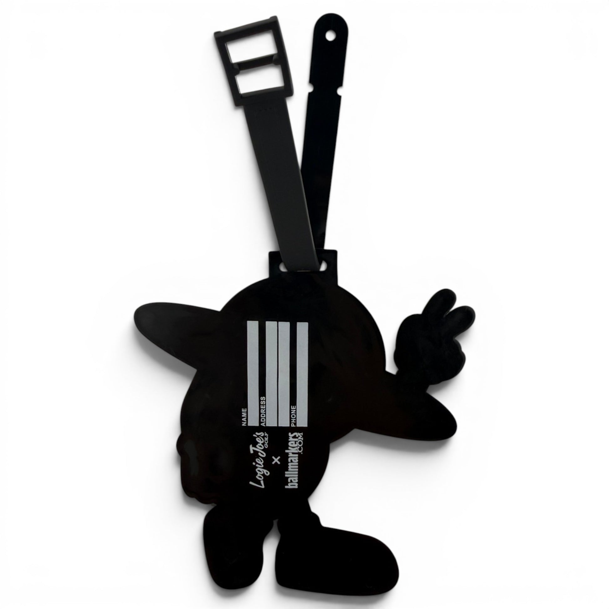 The Saturn Out Clip-On Tag is a black bag tag shaped like a cartoon character with outstretched arms and a hat. It features a strap, barcode-inspired white lines, and printed text on the front—ideal as a multi-use travel or golf accessory.