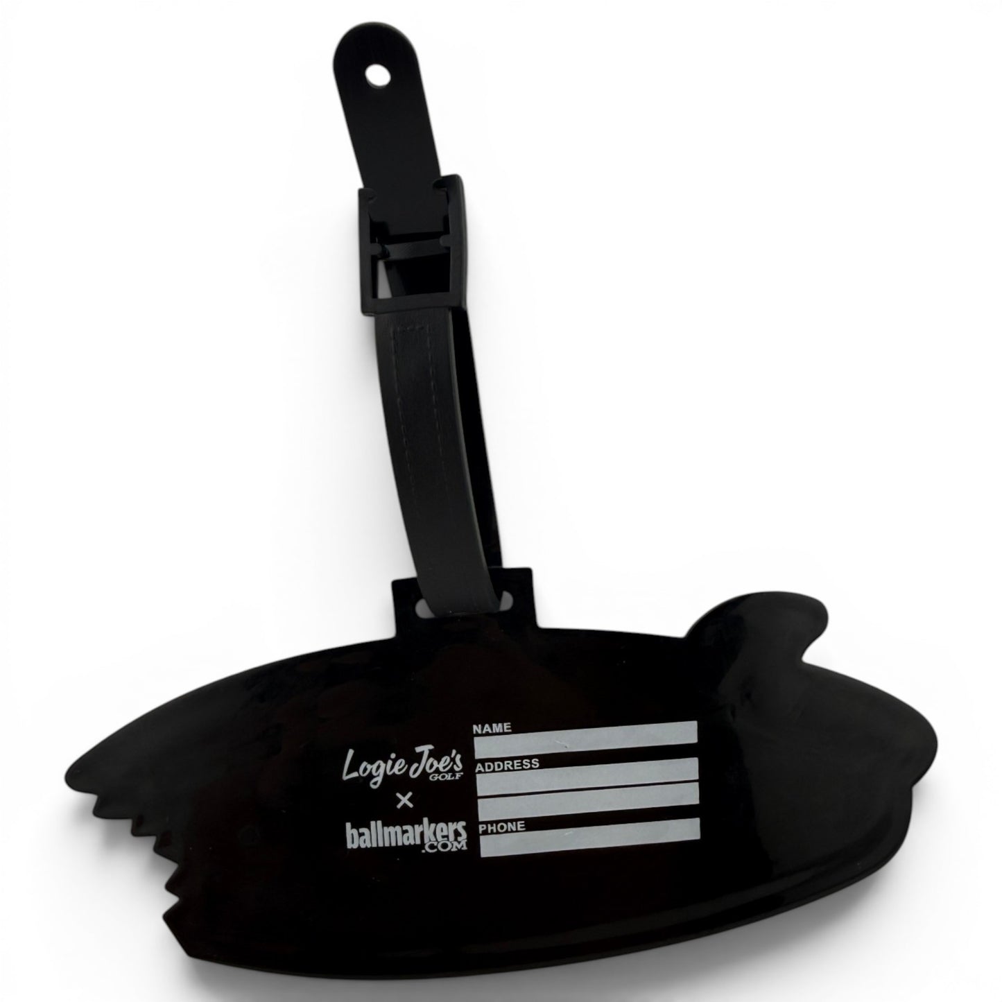 The Shark Bite Clip-On Tag is a black luggage tag shaped like a bitten surfboard, with fields for name, address, and phone. It features Logie Joes x ballmarkers in white and comes with a black strap—ideal as a golf bag accessory.