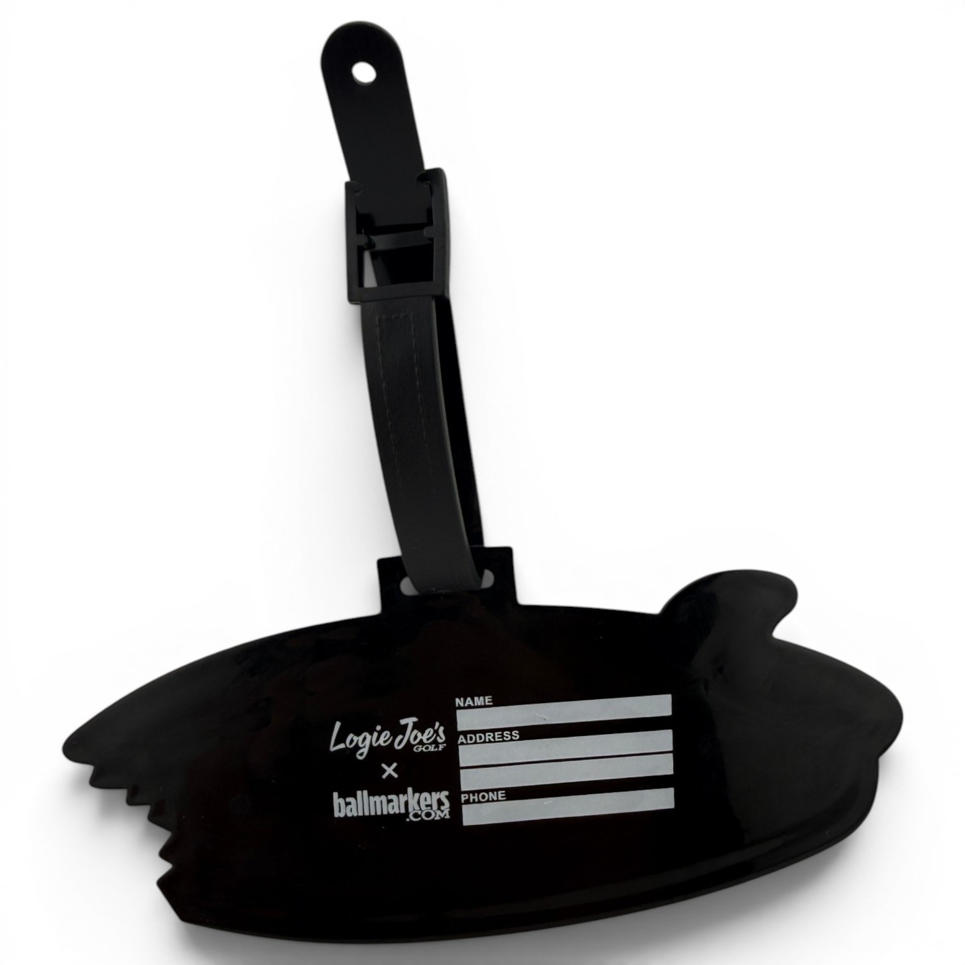 The Shark Bite Clip-On Tag is a black luggage tag shaped like a bitten surfboard, with fields for name, address, and phone. It features Logie Joes x ballmarkers in white and comes with a black strap—ideal as a golf bag accessory.