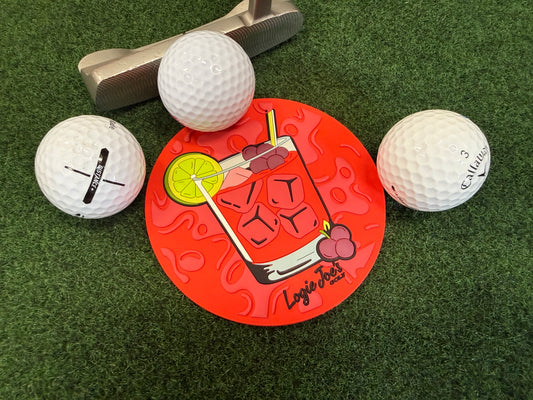 Three golf balls and a putter surround the Transfusion Golf Putting Disc, an indoor practice marker featuring a cocktail illustration and 