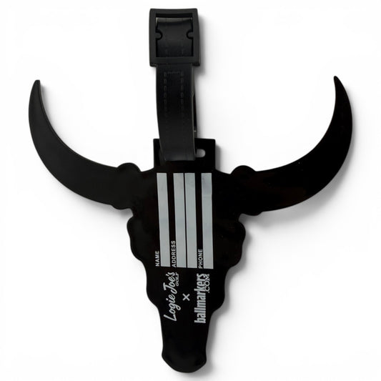 The Longhorn Clip-On Tag is a black, bull head-shaped bag tag with horns, spaces for name, address, and phone, a black strap for easy attachment, and white branding on the front—perfect as a multi-use travel or golf accessory.