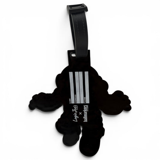 The Deep Dive Clip-On Tag is a black, cartoon-shaped bag tag with three silver stripes and “Luggage tag x balmainskies,” featuring a black strap for easy attachment to your travel or golf bag.