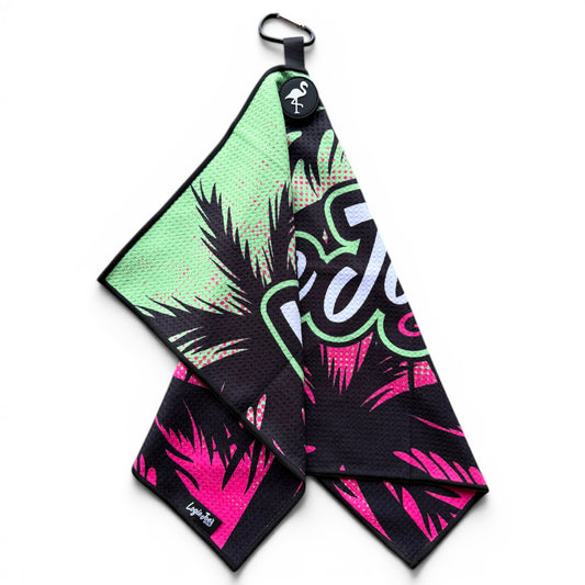 The Neon Palms Golf Towel (24” x 16”) features a black, green, and pink tropical palm leaf design with a white and green script logo, corner loop, magnetic clip, carabiner, and a small flamingo emblem—perfect as a premium golf accessory.