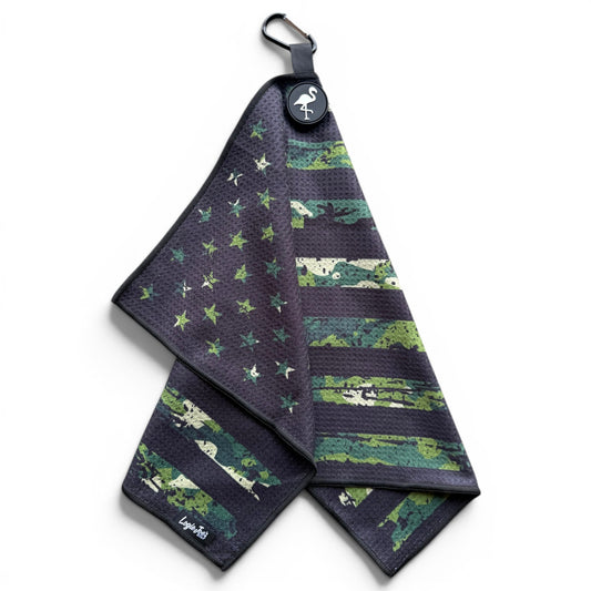 The Tactical Golf Towel is a 24” x 16” dark microfiber towel with a camo American flag, green and black stars and stripes, and comes with a magnetic clip, carabiner, and flamingo logo.