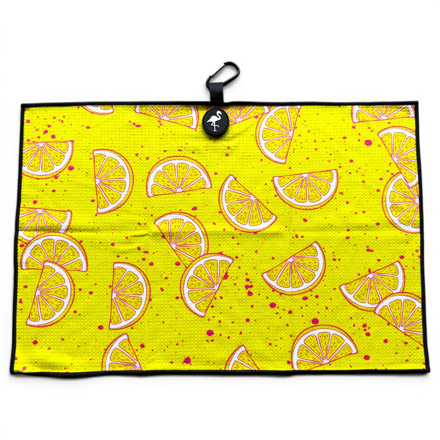 The Main Squeeze Golf Towel is a 24” x 16” yellow microfiber towel with cartoon lemon wedges, pink speckles, black border, and features a magnetic clip, carabiner, and small round logo at the top.