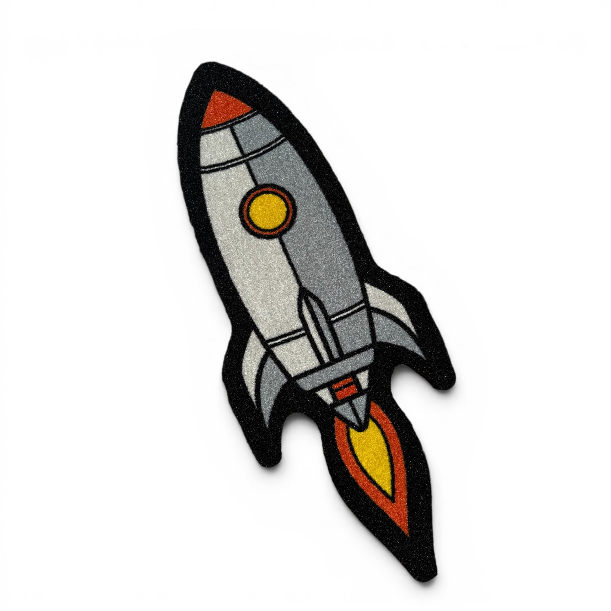 The Pocket Rocket Golf Shop Mat Cart Accessory features a cartoon-style rocket ship with orange accents, a yellow window, black outline, and vibrant flames, inspired by Logie Joe’s artwork on a white background.