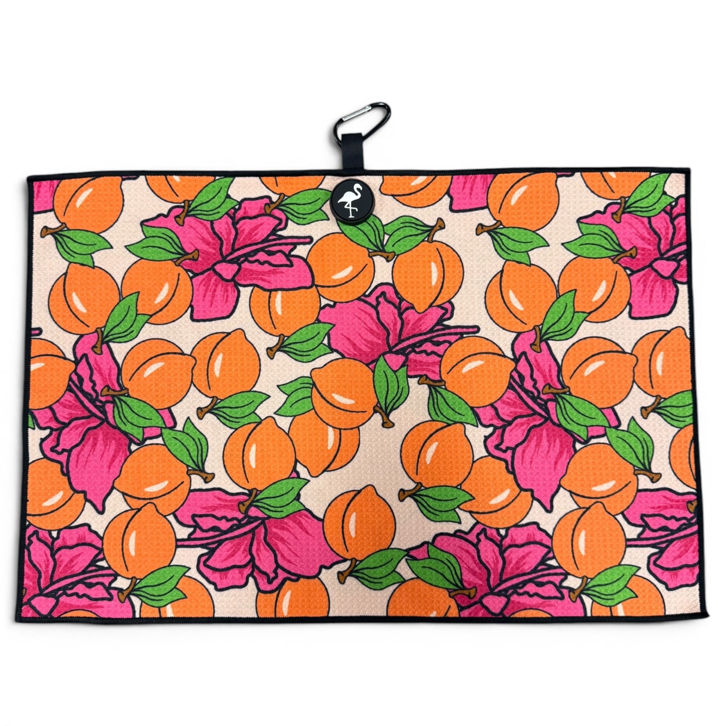 The Peach Bellini Golf Towel features a bright orange fruit and pink hibiscus pattern, green leaves, a black border, and includes a magnetic clip with carabiner. Size: 24” x 16”. Premium microfiber golf accessory.