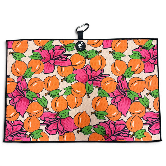 The Peach Bellini Golf Towel features a bright orange fruit and pink hibiscus pattern, green leaves, a black border, and includes a magnetic clip with carabiner. Size: 24” x 16”. Premium microfiber golf accessory.