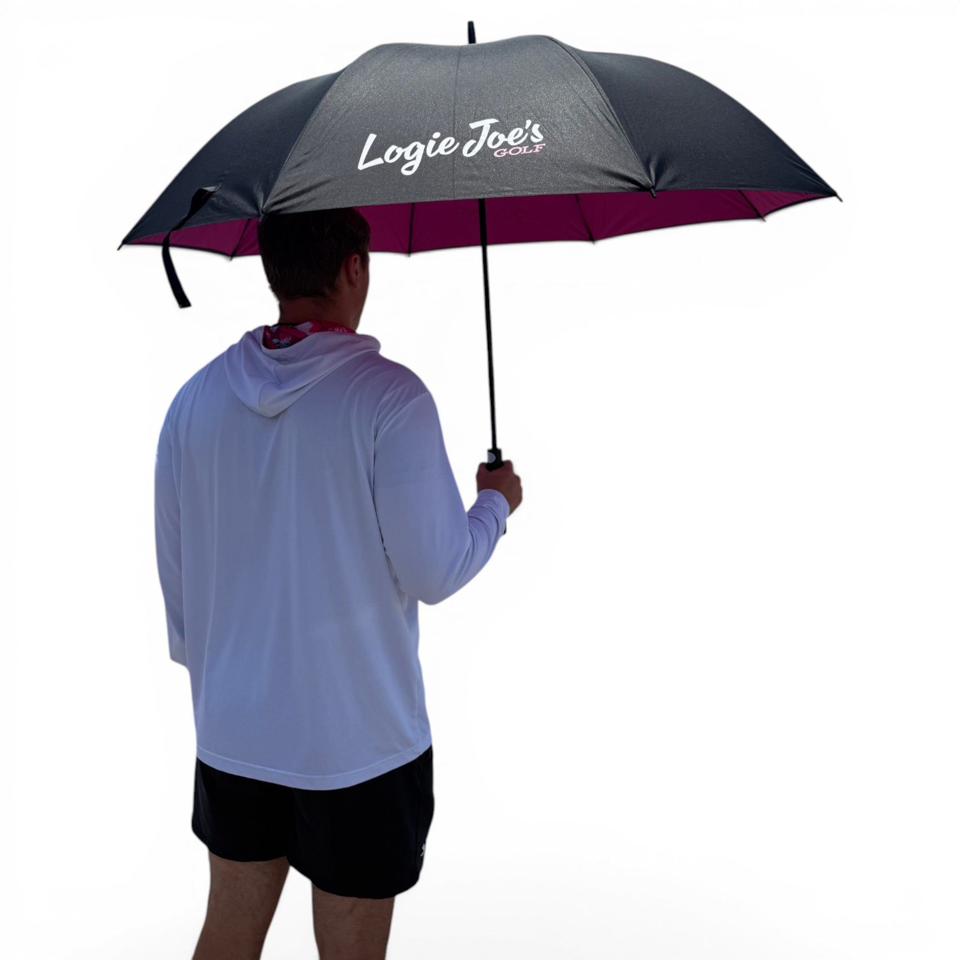 A person in a white hoodie and black shorts holds the 60" Oversized Black & Pink Golf Umbrella against a plain white background, facing away from the camera.