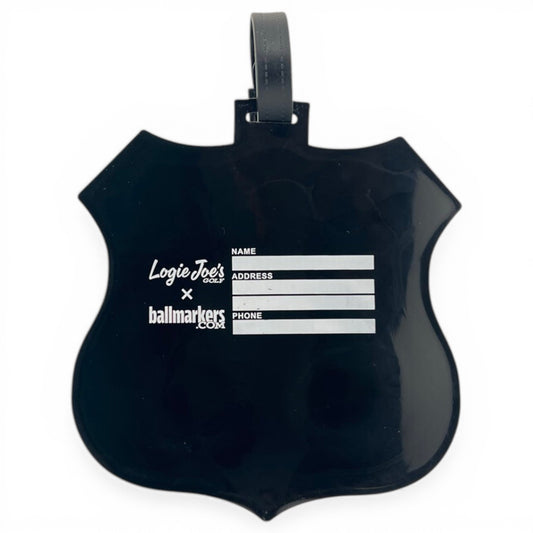 The RT 66 Clip-On Tag is a black, shield-shaped multi-use bag tag and golf accessory by Logie Joes Golf x ballmarkers.com. It has spaces for name, address, and phone with a top loop for easy travel or golf bag attachment.