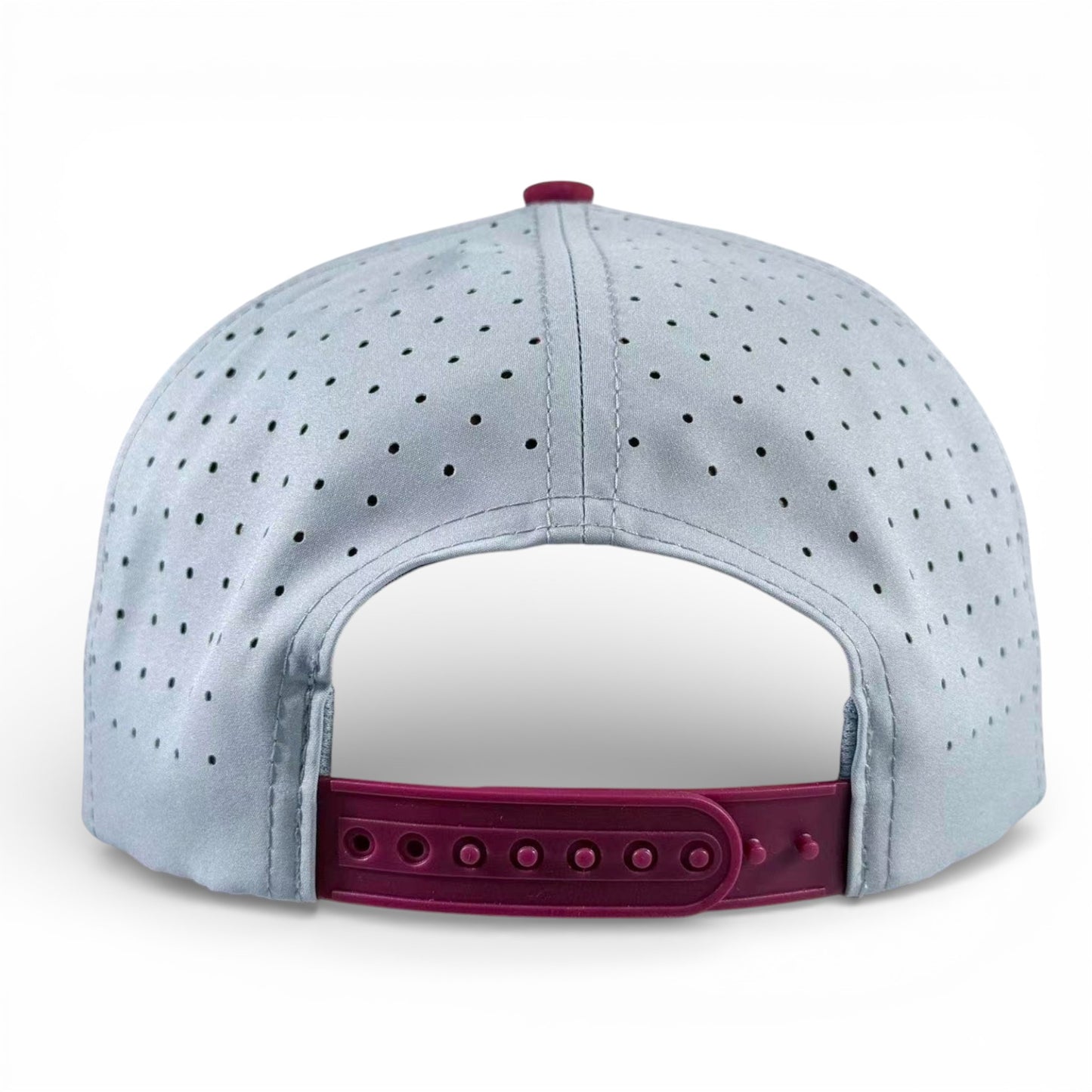 The Transfusion Golf Hat is a light gray adjustable snapback cap, viewed from the back, featuring small ventilation holes and a dark pink closure. It includes a built-in magnetic ball marker holder with marker.