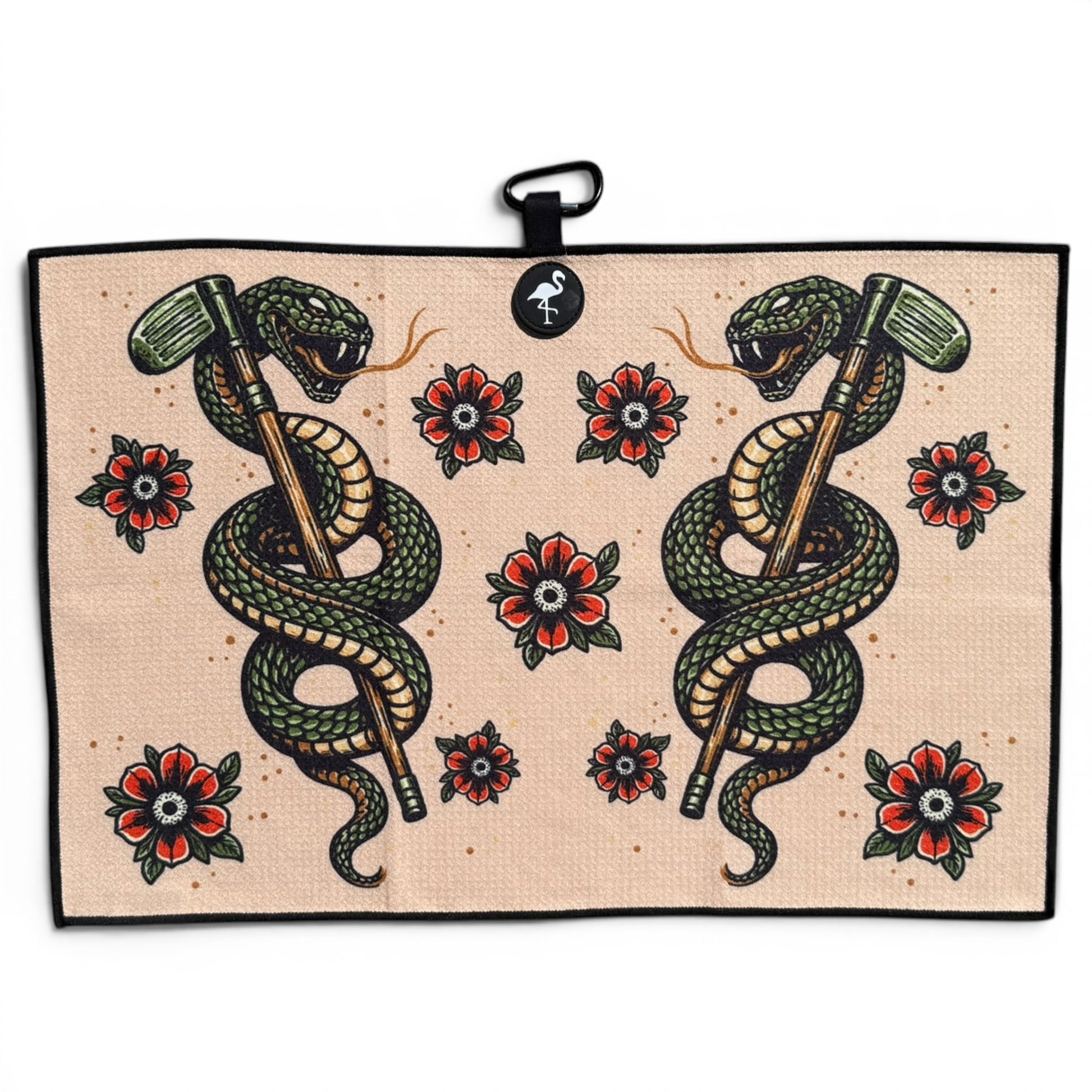 The Desert Serpent Golf Towel (24” x 16”) is a beige microfiber towel with two green snakes wrapped around axes, facing each other among red and black flowers, featuring a magnetic clip and carabiner for easy attachment.