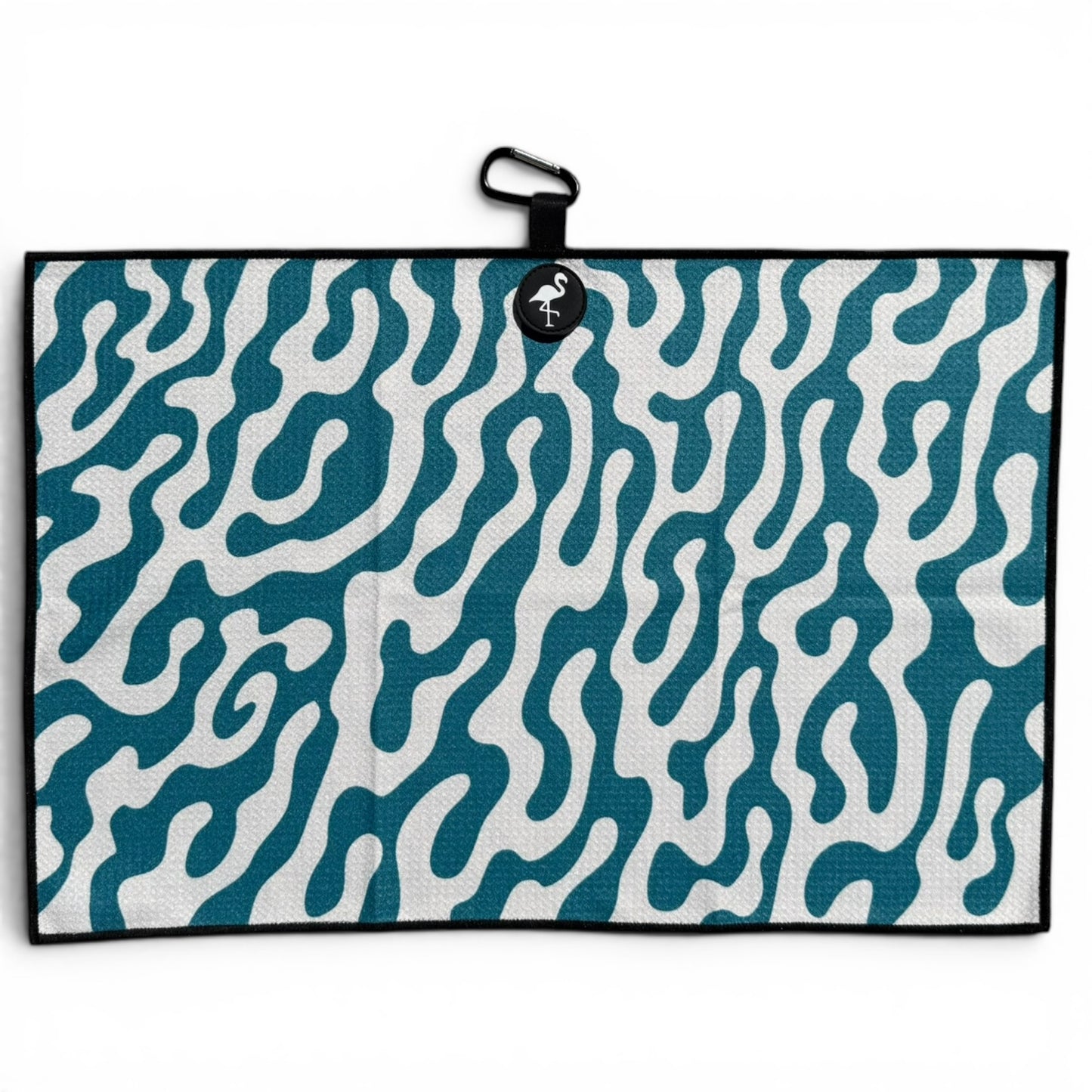 The Coral Bloom Golf Towel is a 24” x 16” microfiber towel in teal and white with an abstract wavy pattern, a black border, a black loop, flamingo tag at the top, plus magnetic clip and carabiner for easy attachment.