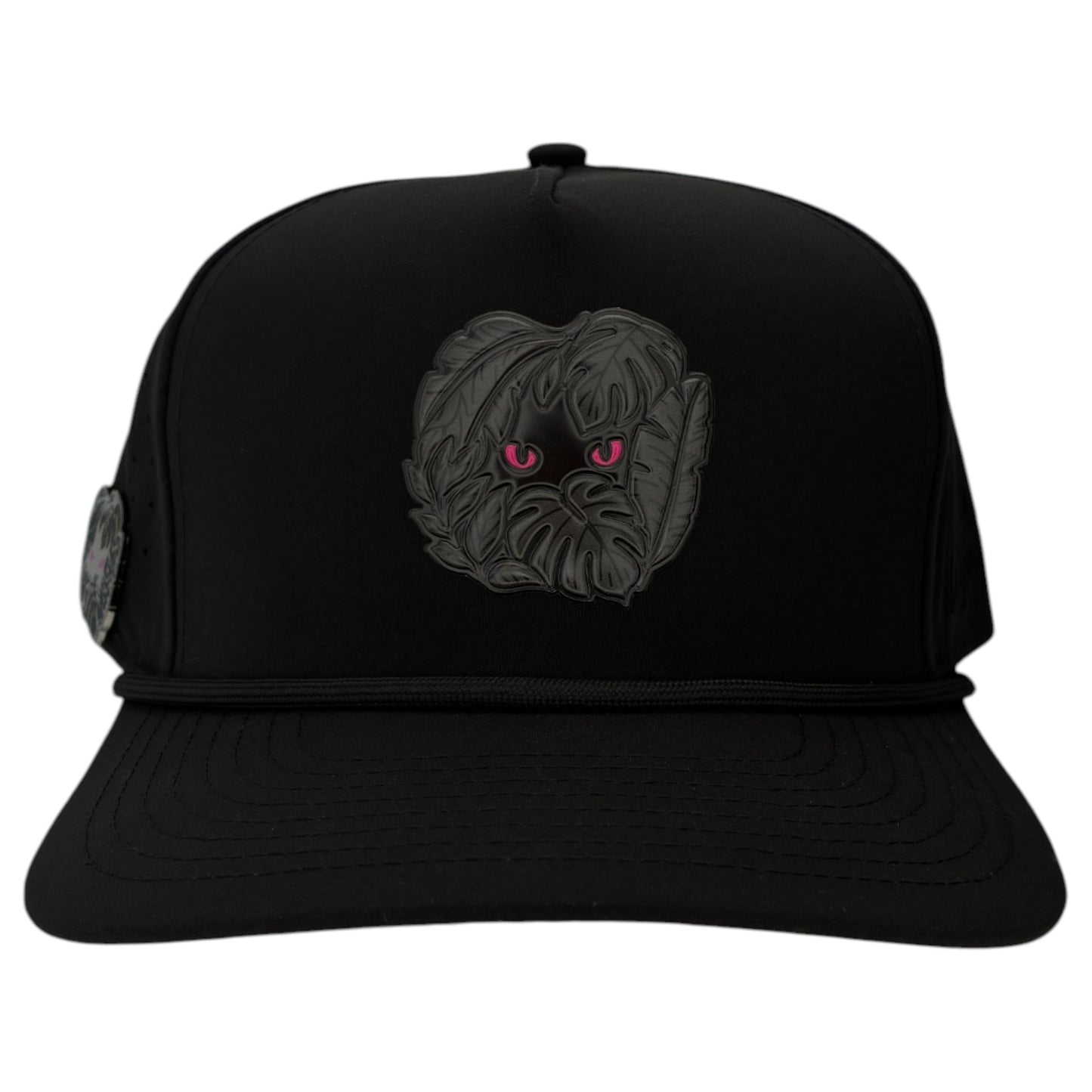 The Night Stalker Golf Hat is a black snapback cap with animal eyes, a flat brim, decorative cord, and an adjustable fit. It features a built-in magnetic ball marker holder and includes a marker for added convenience.
