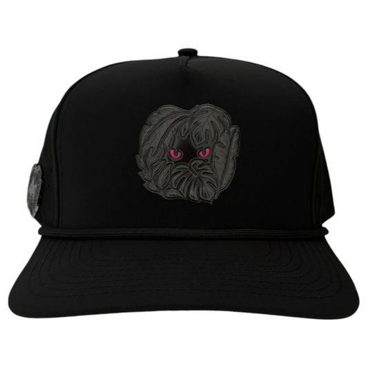 The Night Stalker Golf Hat is a black snapback cap with animal eyes, a flat brim, decorative cord, and an adjustable fit. It features a built-in magnetic ball marker holder and includes a marker for added convenience.