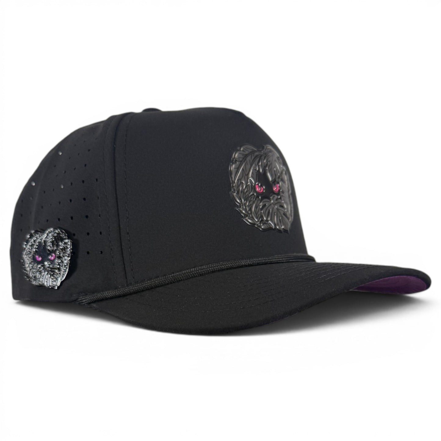 The Night Stalker Golf Hat—an adjustable black snapback cap with animal eyes—features two embroidered dog faces with pink eyes, perforated holes, and a built-in magnetic ball marker holder plus marker on the side panel.
