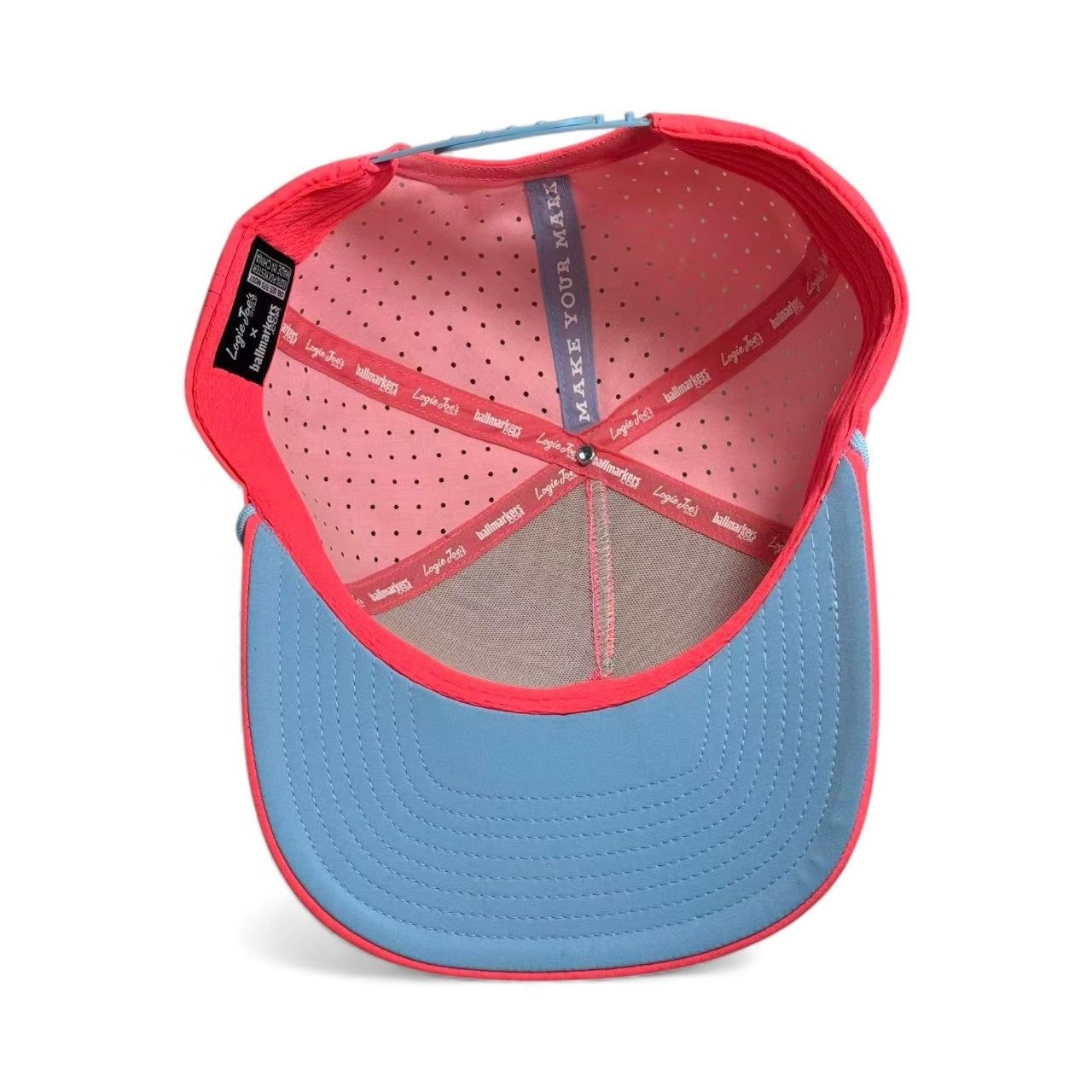Inside view of the Frosted Elephant Golf Hat – Snapback Cap in Elephant Cookie Pink, with a light blue brim, red interior, perforated pink fabric, branded tags, and a built-in magnetic ball marker holder (marker included).