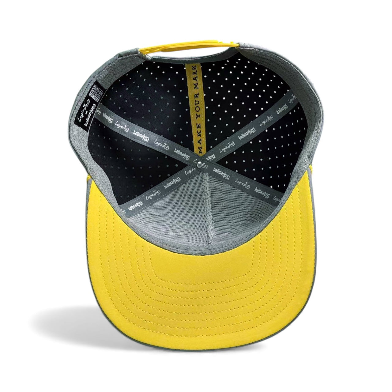 Top view of the Alien Gray UFO Golf Hat, featuring inner lining, polka-dot fabric, label tags, and "MAKE YOUR MARK" on a yellow band—an adjustable snapback cap with built-in magnetic ball marker holder and marker included.