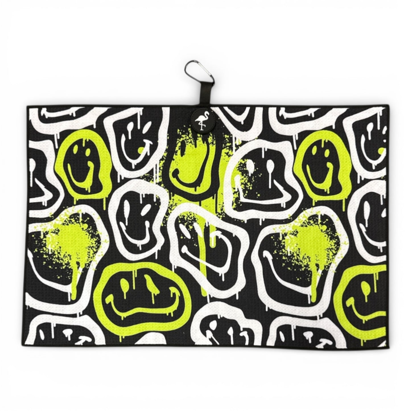 The Drippy Smile Golf Towel (24x16 in) features abstract white and neon yellow drippy smile faces on a black microfiber backdrop, paint splatter accents, and includes a heavy-duty magnetic back plus carabiner clip for easy access.