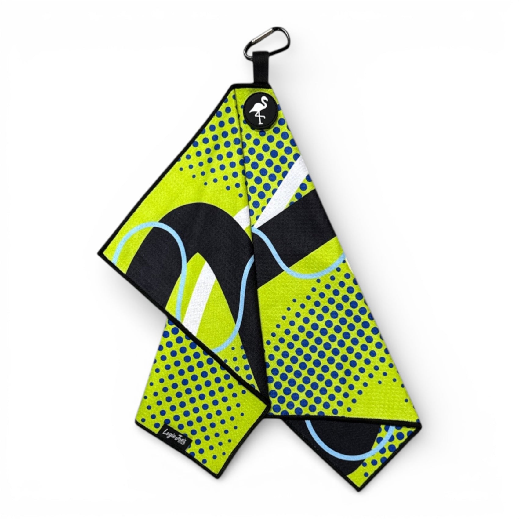 The Neon Current Golf Towel is a 24x16 in double-sided microfiber towel in yellow, black, blue, and white with bold geometric and dotted patterns. Features include a carabiner clip, heavy-duty magnet, and a flamingo tag. Shown hanging on a white background.