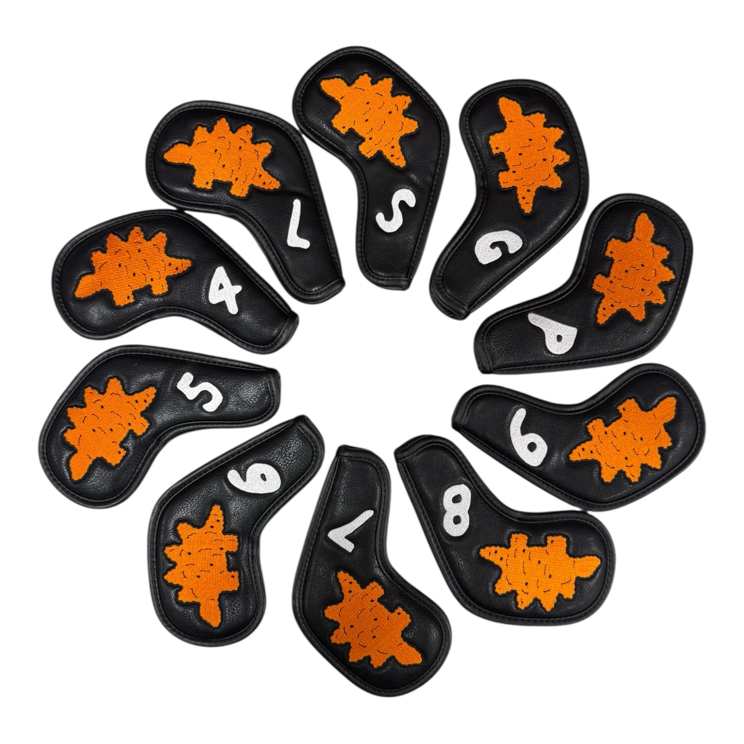 The Dino Nugget Stegosaurus Golf Iron Cover Set includes 10 black PU leather covers (4–9, PW, GW, SW, LW), each with a turtle-shaped orange patch and white markings. Magnetic closures keep your clubs protected and organized.