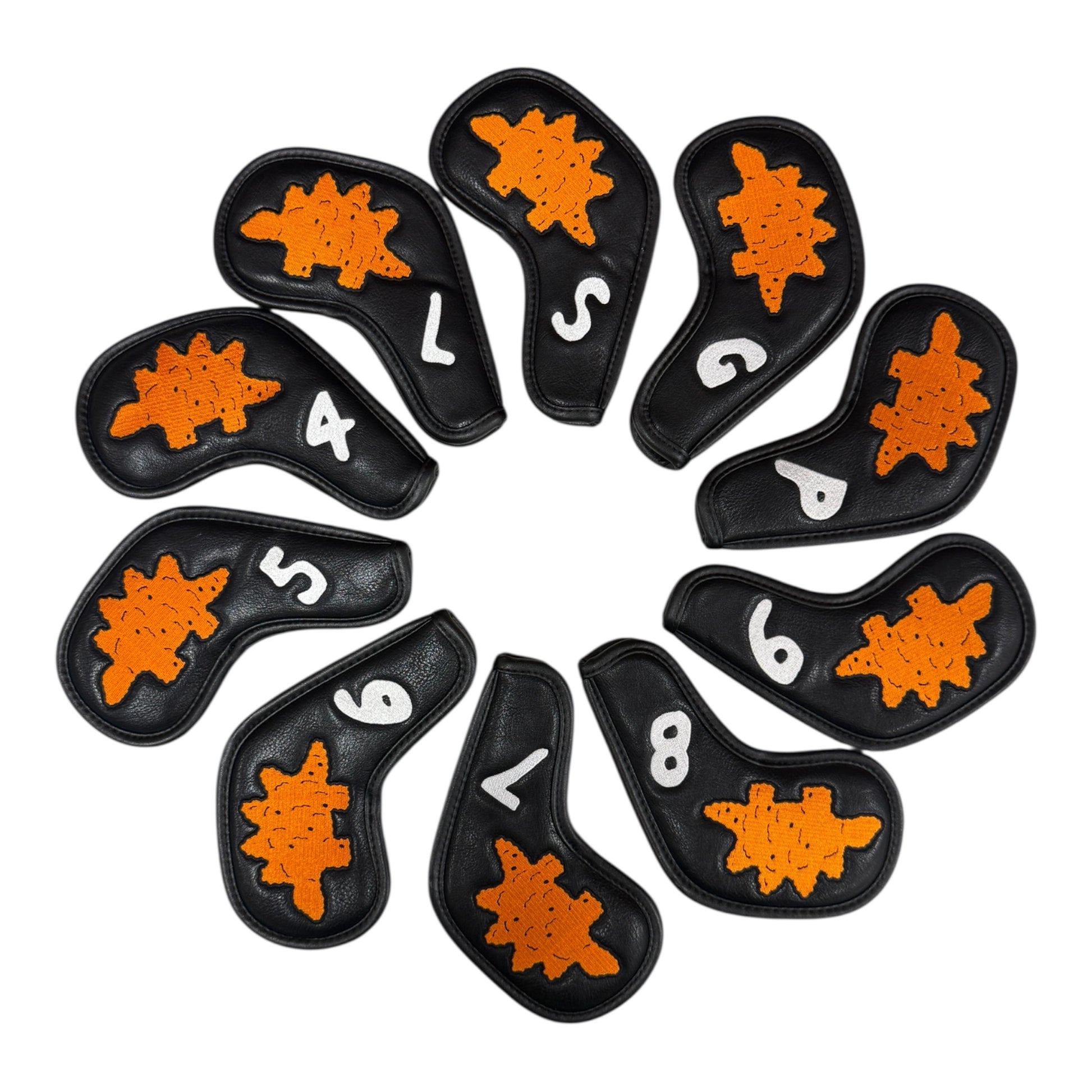 The Dino Nugget Stegosaurus Golf Iron Cover Set includes 10 black PU leather covers (4–9, PW, GW, SW, LW), each with a turtle-shaped orange patch and white markings. Magnetic closures keep your clubs protected and organized.